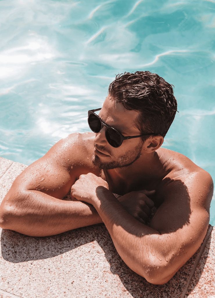 Man relaxing by a pool wearing Bask sunglasses