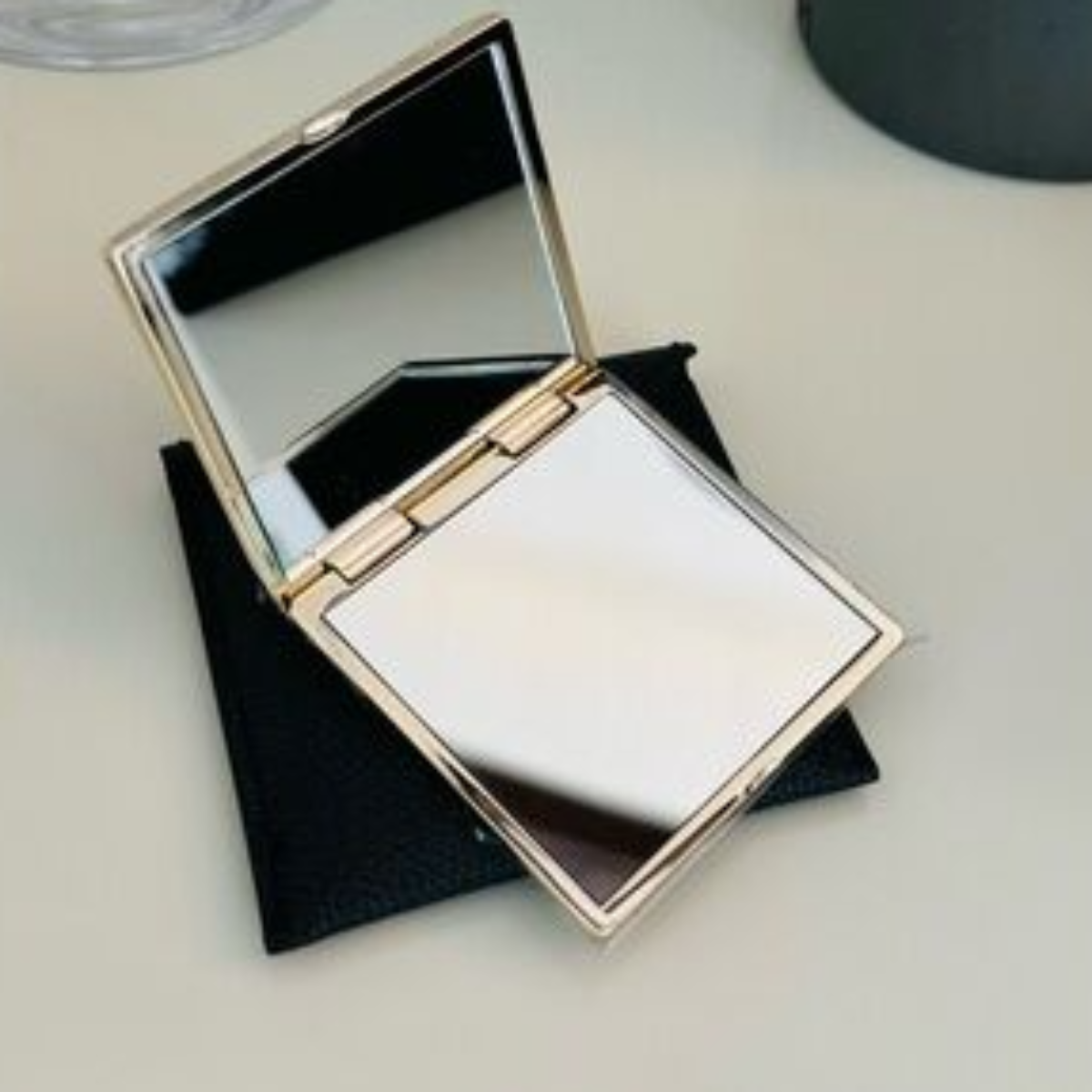 Compact mirror with a black case on a light surface